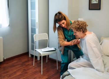 Caregiver helping elderly patient to get out of bed